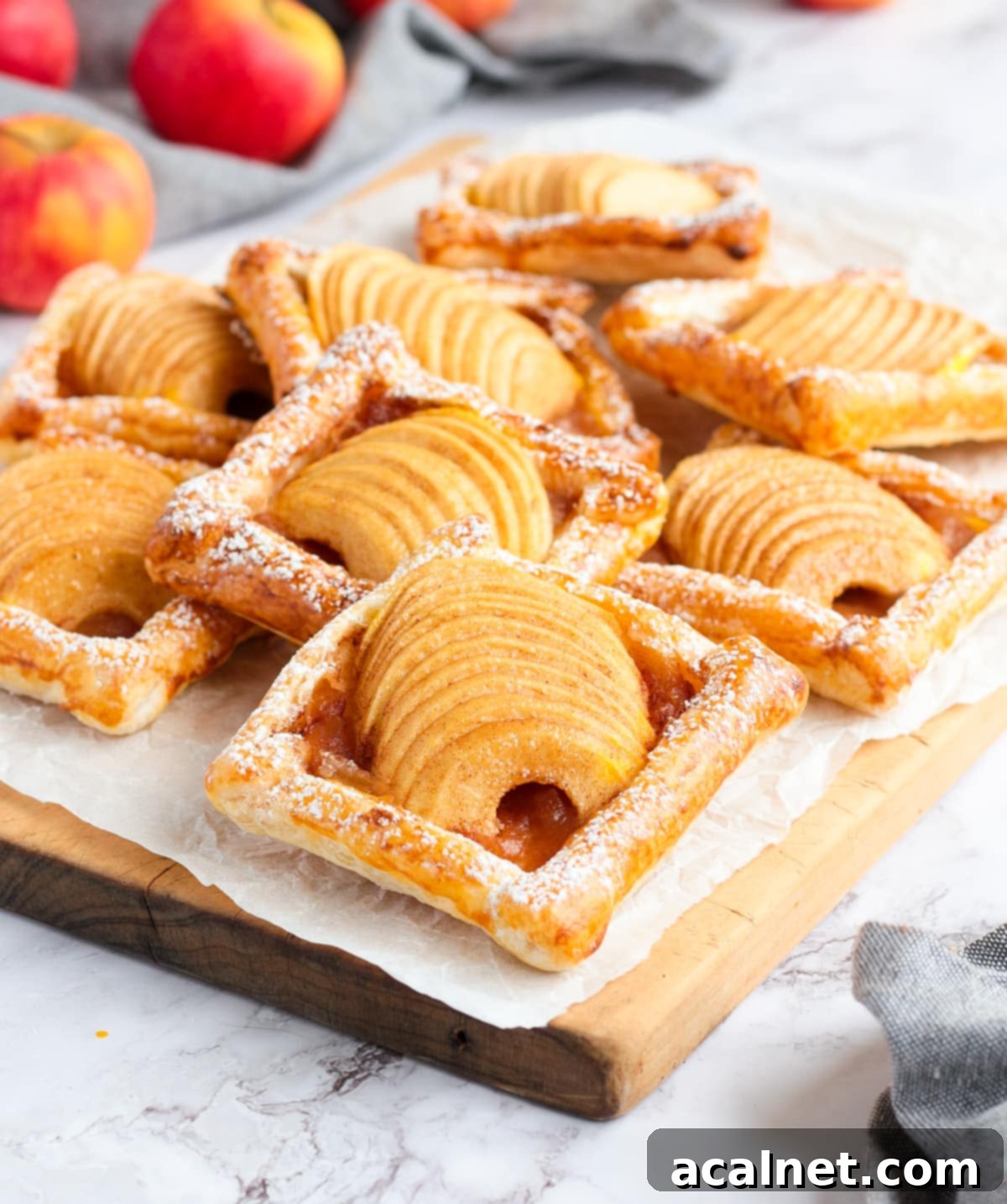 Flaky Apple Bites 6 Stack of tarts over a wooden cutting board and a sheet of white baking paper.
