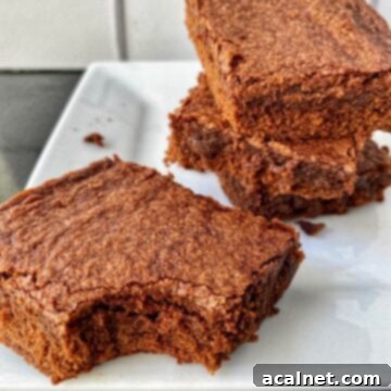 A stack of sliced brownies, one with a bite out of it.