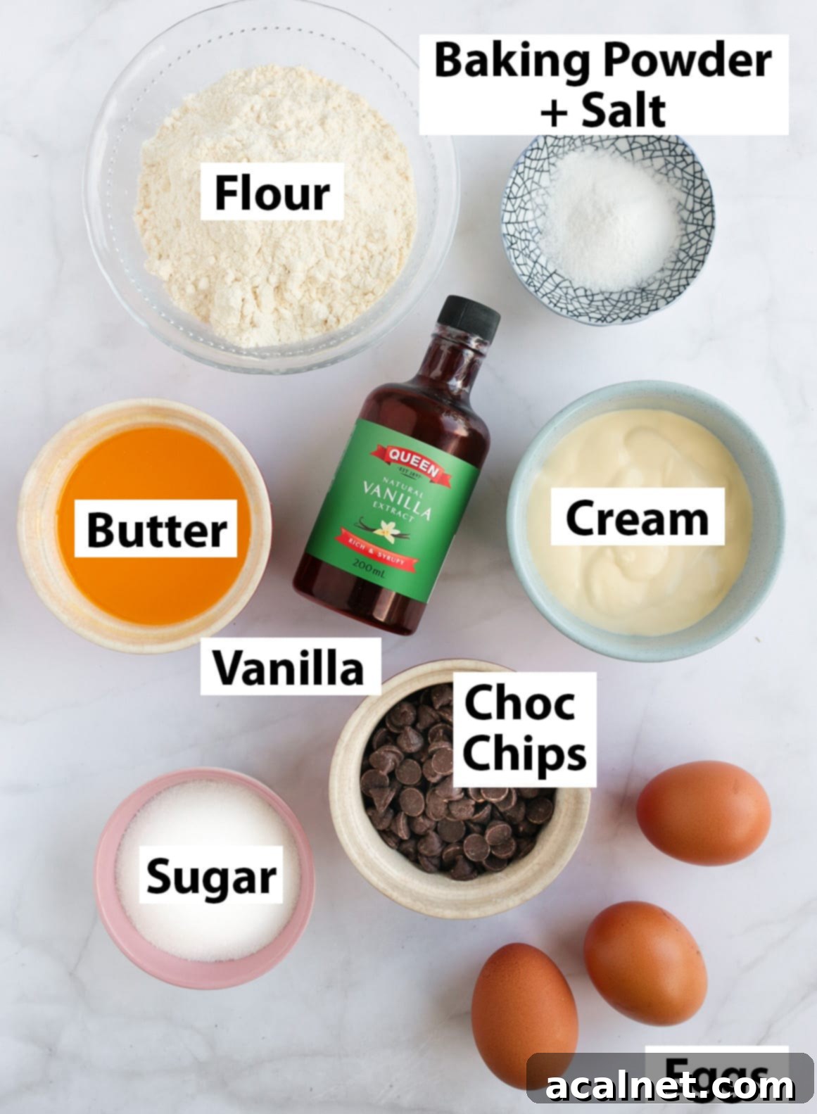 A flat lay of all ingredients for Chocolate Chip Loaf Cake, including eggs, sugar, flour, butter, cream, vanilla, baking powder, salt, and chocolate chips.