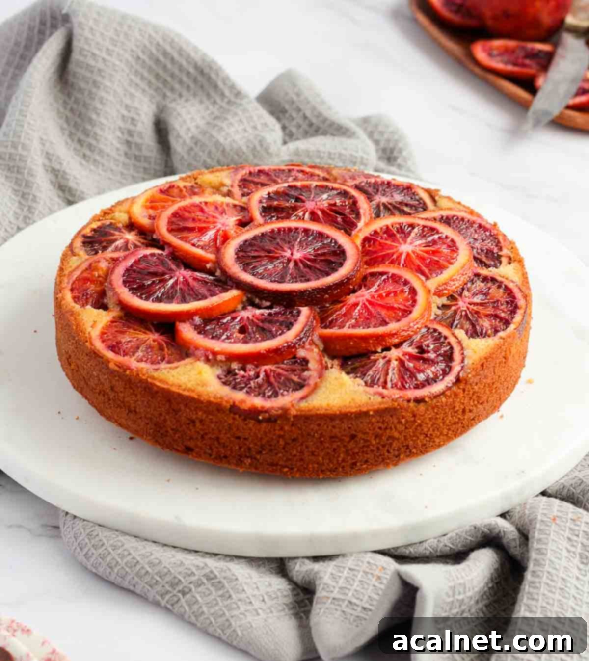 Blood Orange Cake on a white marble board over a grey napkin, with a slice removed.