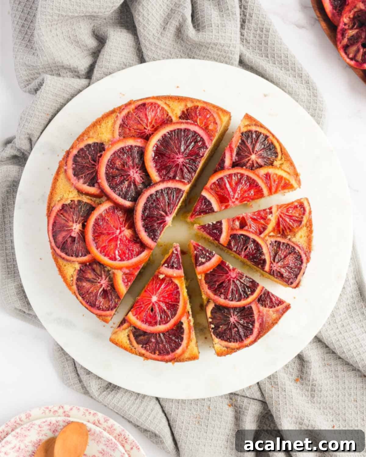Half Sliced Blood Orange Upside Down Cake on a white plate from above.