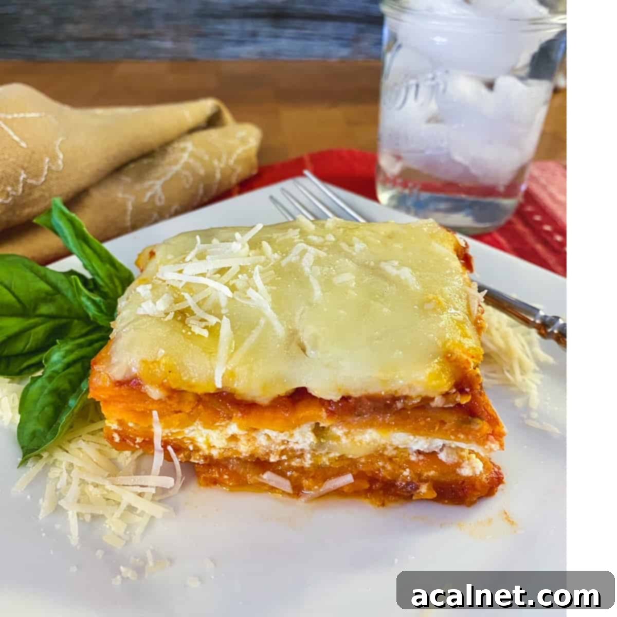 Sweet Potato Lasagna Perfection 17 A slice of golden-brown sweet potato lasagna served on a plate, accompanied by a refreshing glass of ice water.