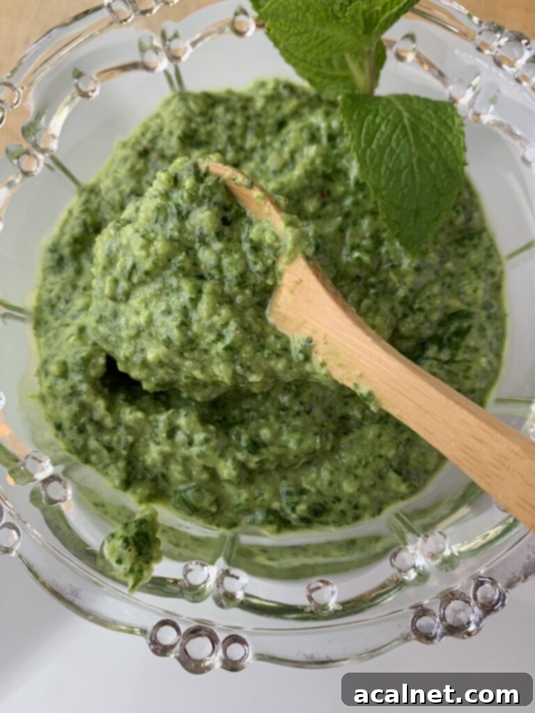 Pesto sauce being spooned into a bowl of ingredients