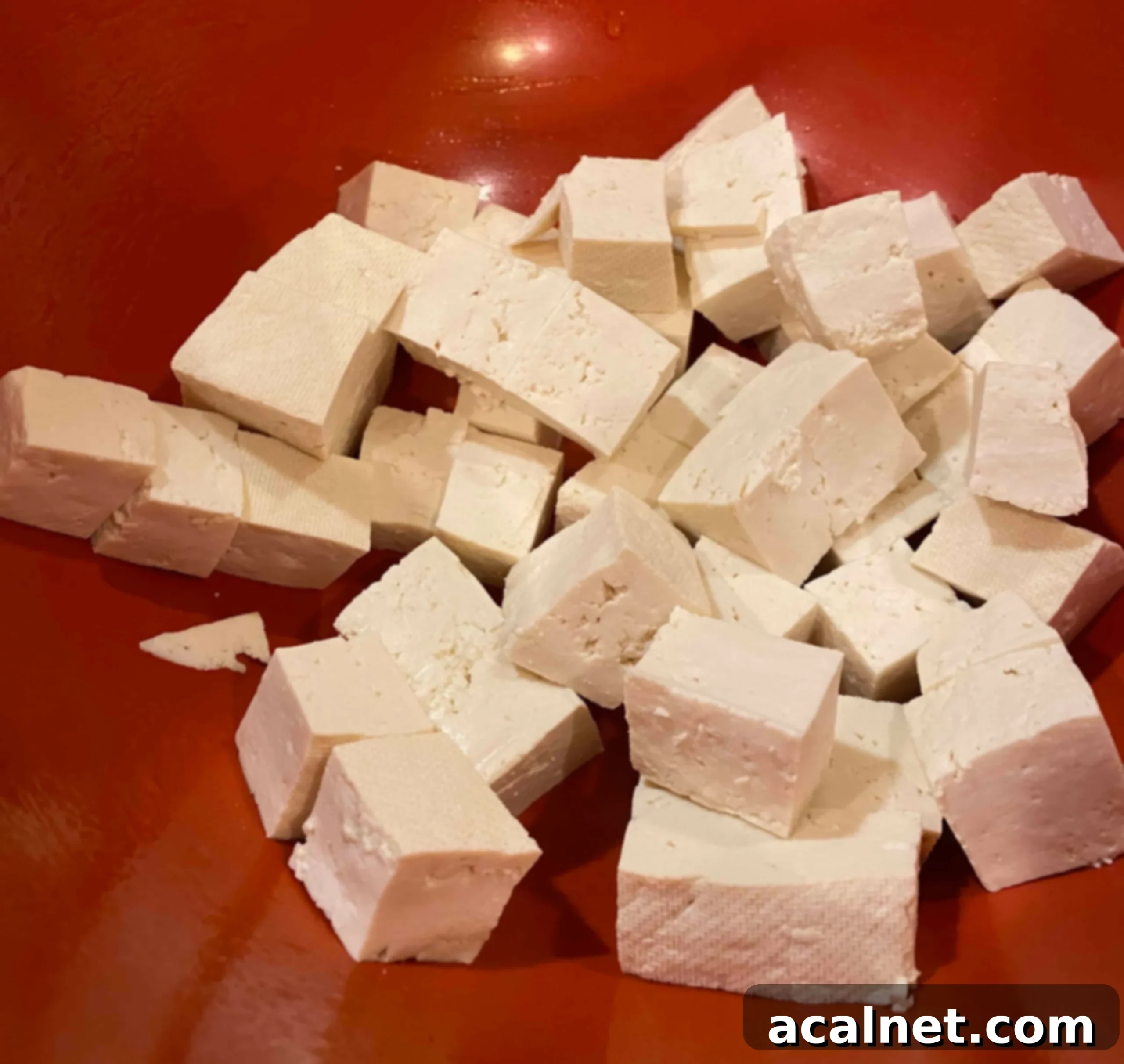 Diced, uncooked tofu in a bowl, showing its texture after pressing.