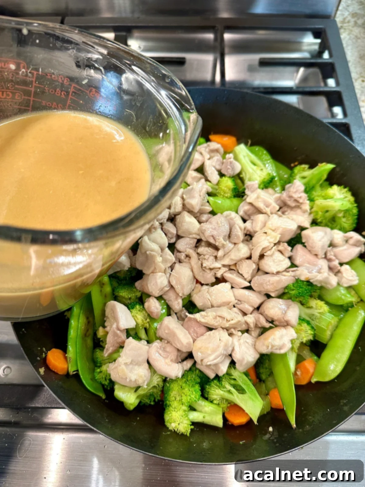 Chicken and Cashew Stir-Fry 10 A cup of sauce for cashew chicken stir fry over a pan of veggies and chicken.