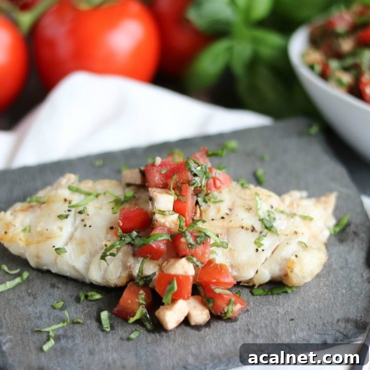 One portion of grilled fish on slate plate with topping and fork; extra topping and ingredients in background.