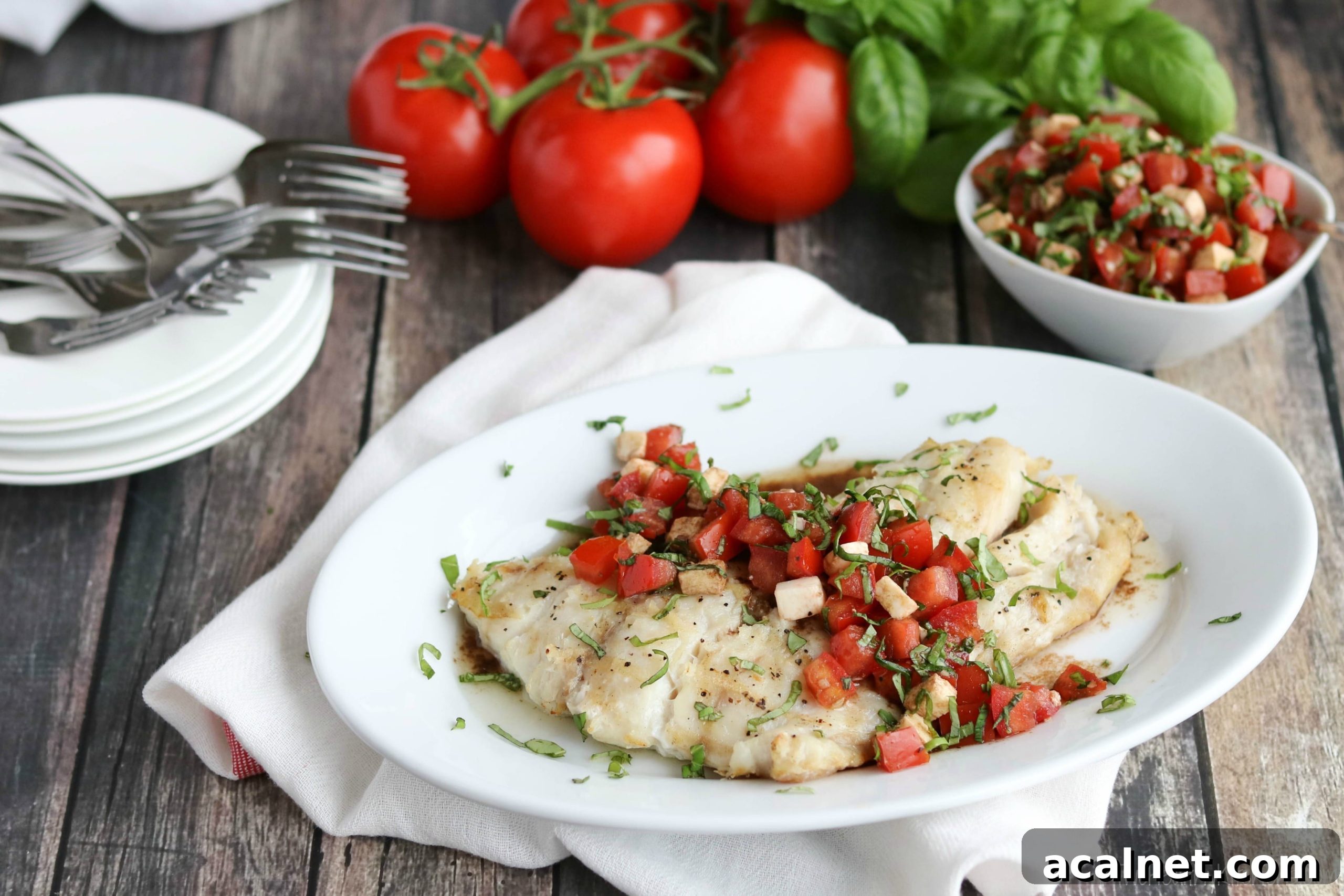 Caprese Grilled Fish Whole horiz Watermarked Whole grilled fish filet with caprese topping across, on white serving platter surrounded by ingredients.
