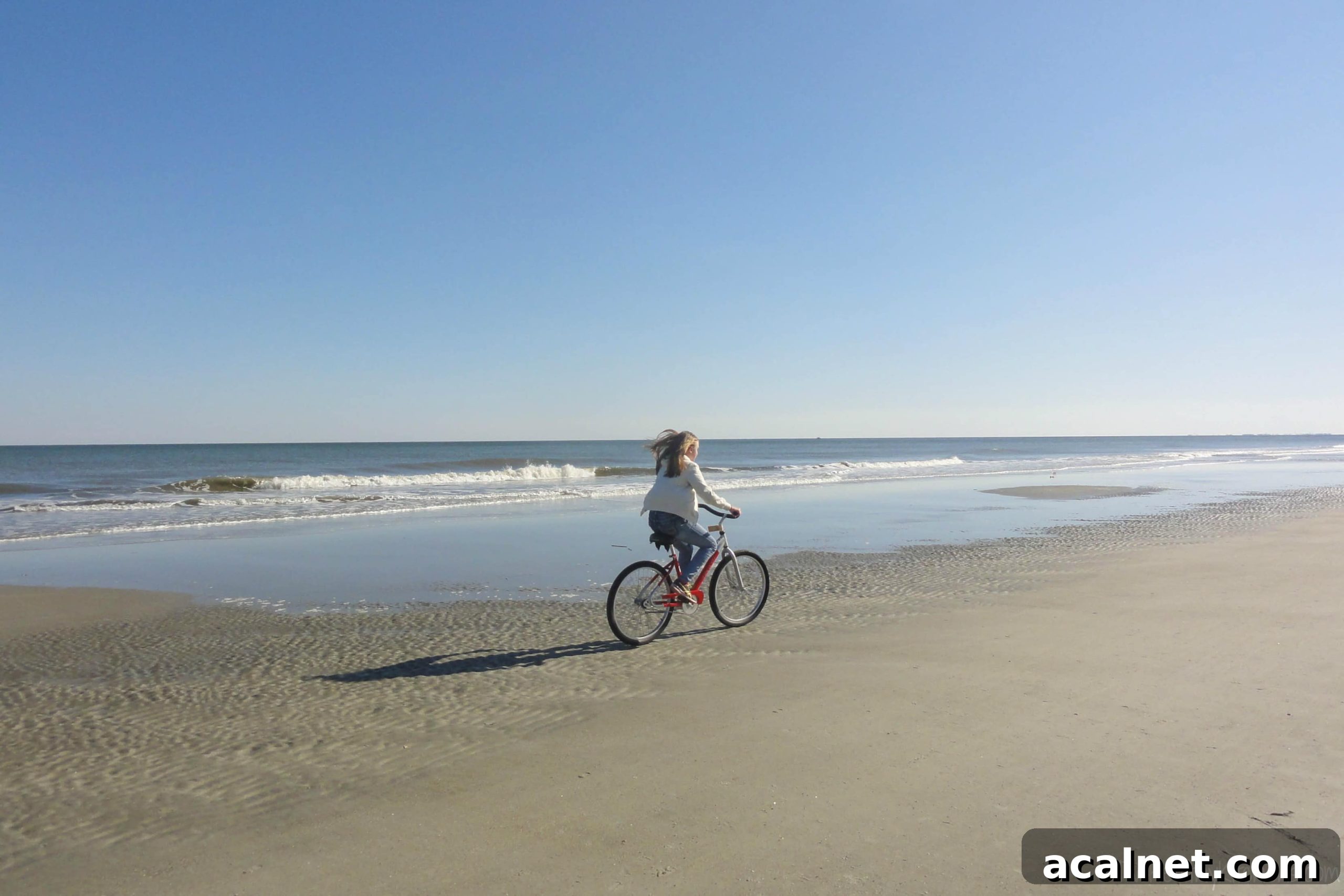 Caprese Grilled Fish Amy Biking Watermarked Girl in jeans and jacket riding red bike on beach at surf line.