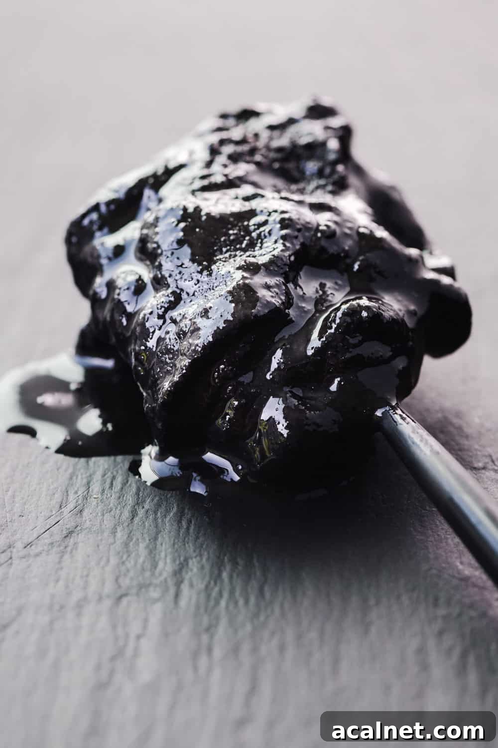 Black tahini on a black spoon on black slate