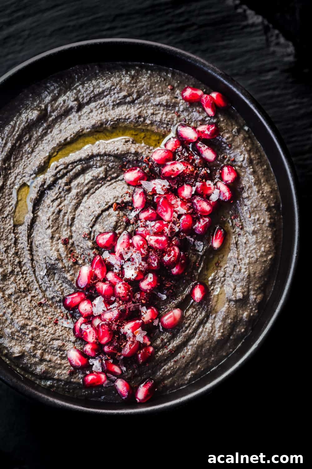 black hummus with pomegranate arils, flaky sea salt, sumac and olive oil