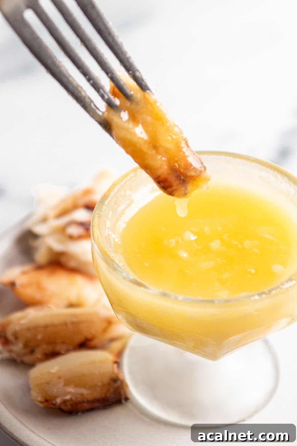 Garlic Butter Seafood Sauce Recipe for Shrimp, Scallops & Fish 2 A fork dipping a piece of crab into a bowl of garlic butter.