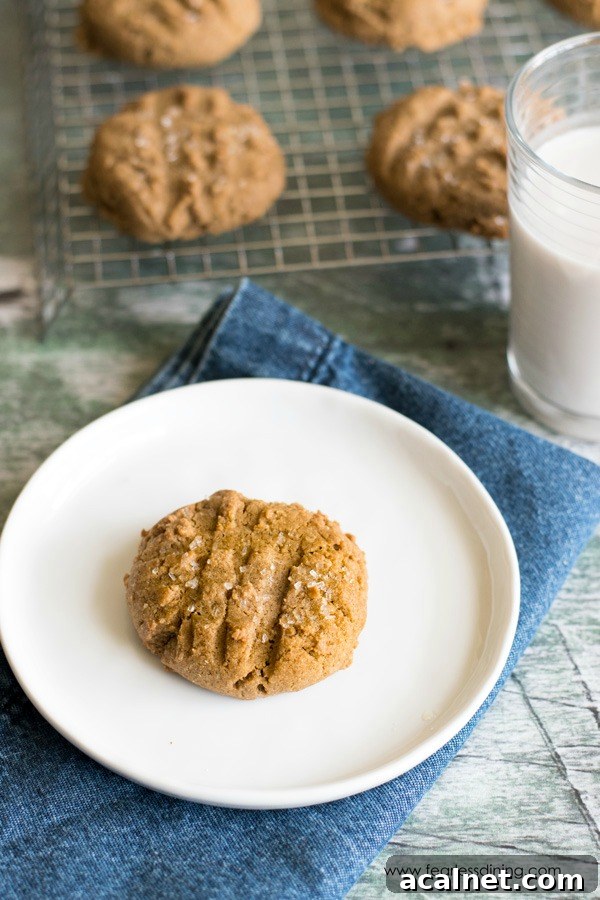 A gluten free molasses cookie on a plate next to a rack of cookies.