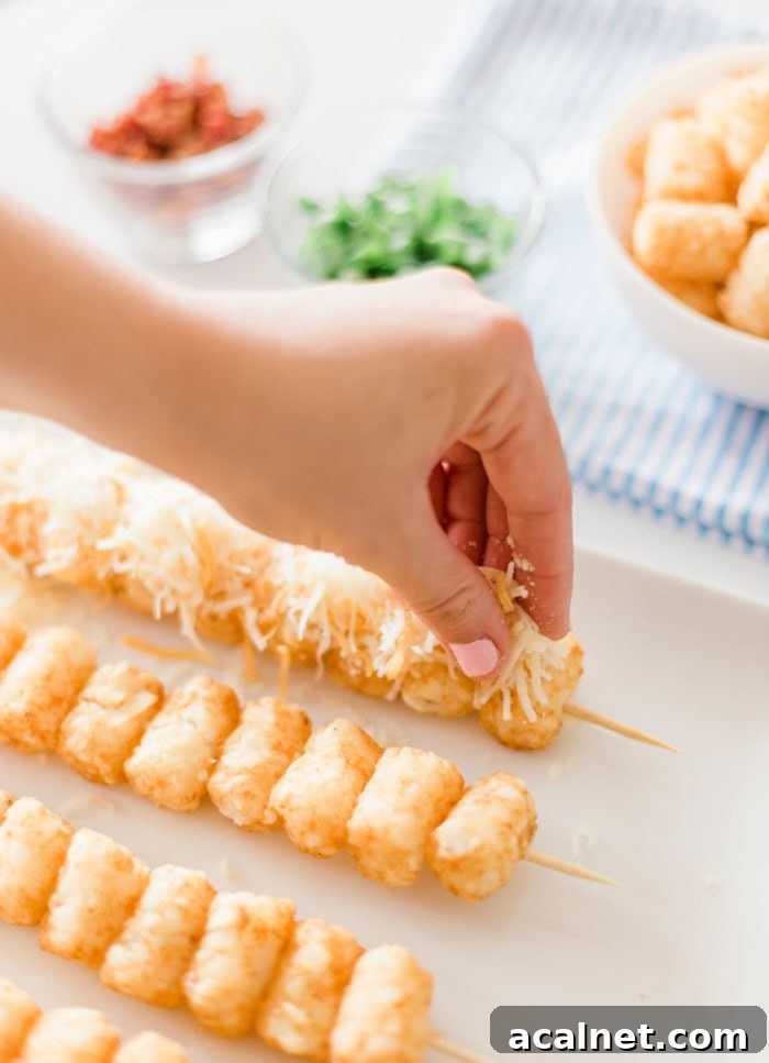 Sprinkling cheese over skewered tater tots