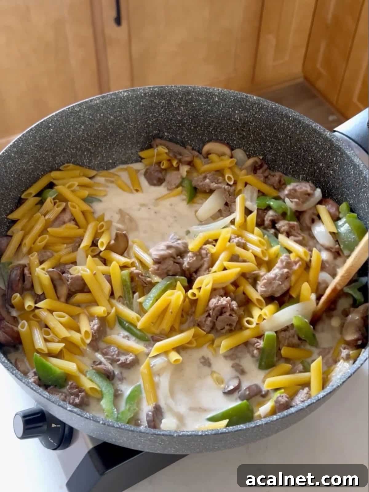 Sauce and pasta added to the sauté pan of meat and veggies.