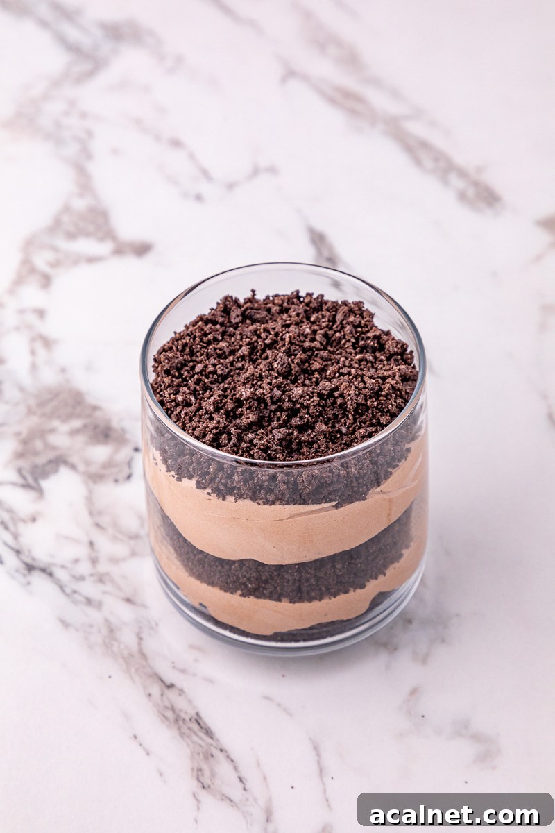Layered pudding mixture and crushed Oreos in glass.