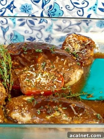 Balsamic chicken with tomatoes in a glass dish with aqua blue spatula