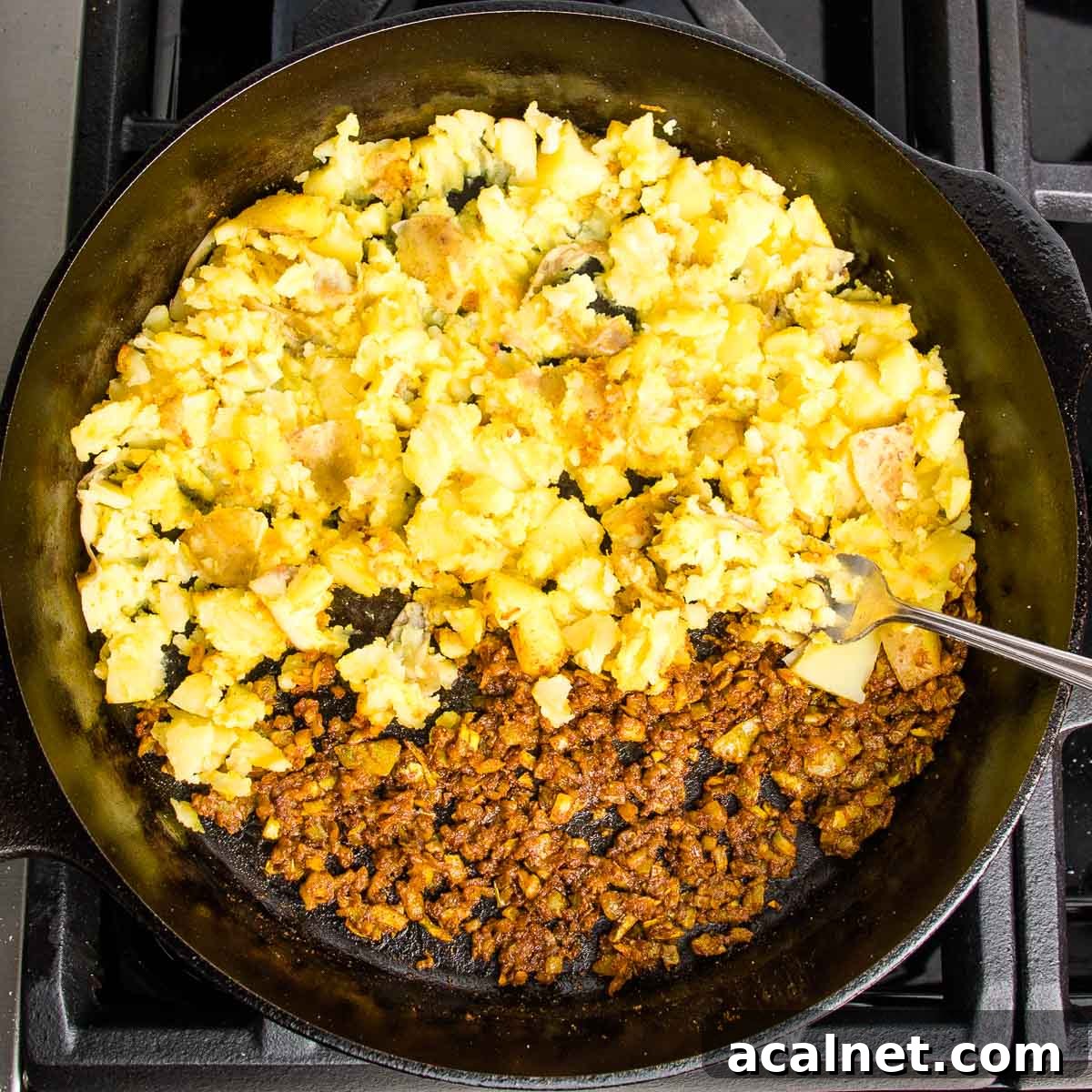 Cast iron skillet half filled with onion/garlic/spice mixture and the other half has diced boiled potatoes