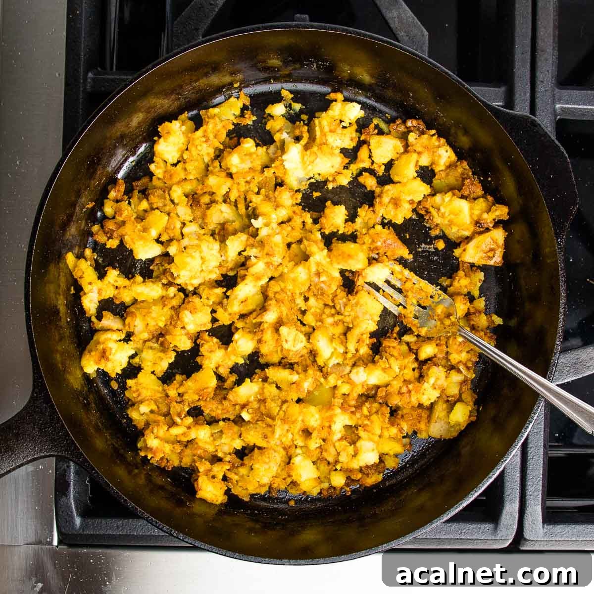 Cast iron skillet filled with potatoes, onions, garlic and spices that have been sauteed.