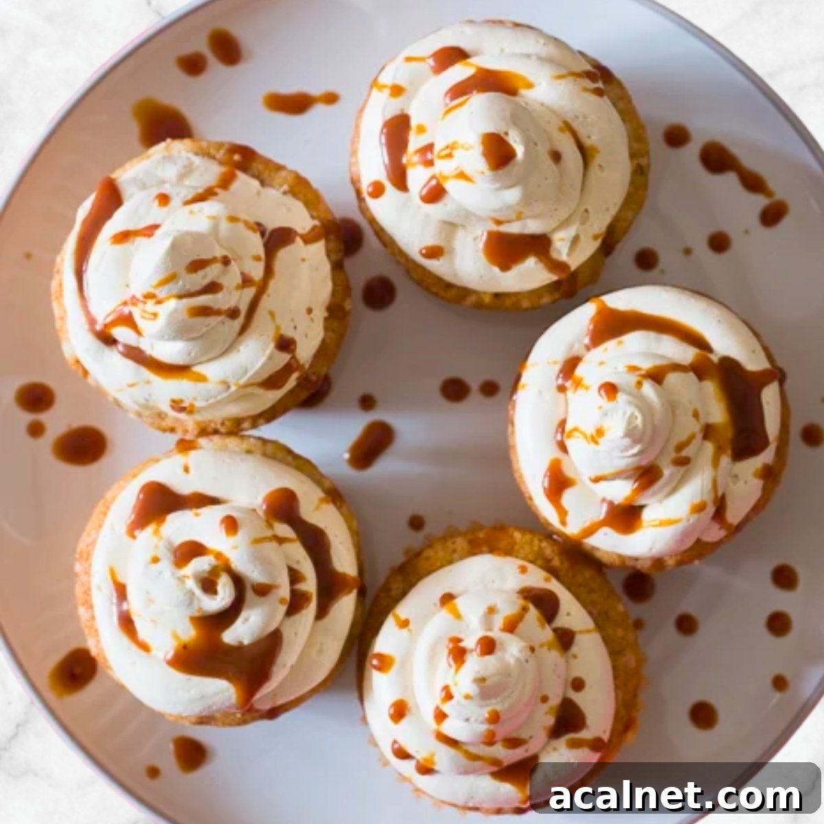 Moist apple cupcakes with cream cheese frosting and caramel drizzle on top, perfect fall dessert.