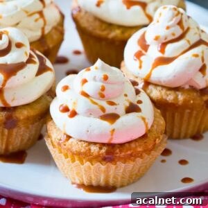 close-up of caramel apple cupcakes topped with cinnamon cream cheese frosting and drizzled with caramel sauce.