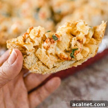 holding a piece of new orleans style crawfish bread, showing crawfish and cheesy sauce.