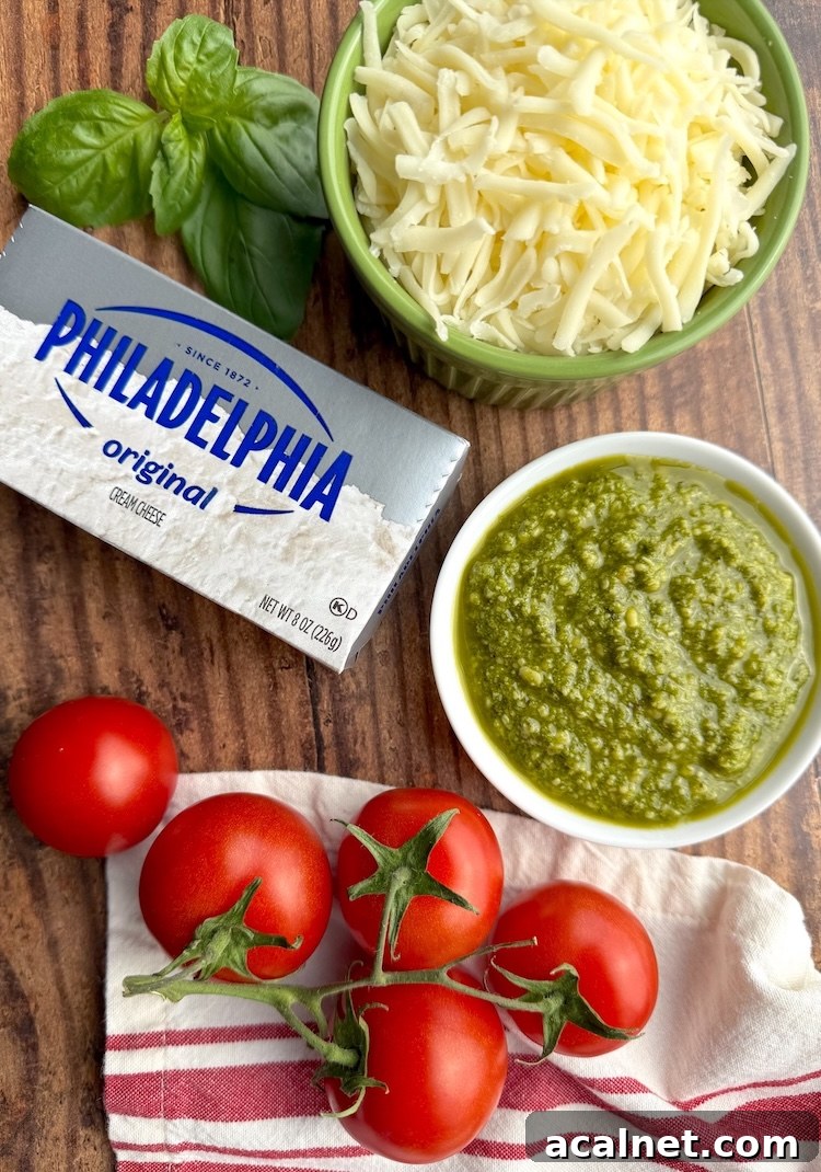 List of ingredients need to make creamy pesto baked chicken including chicken breasts, cream cheese, basil pesto, mozzarella, fresh basil, and tomatoes. 