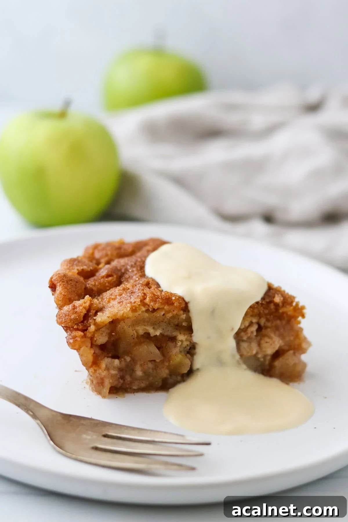 Swedish Crustless Apple Pie on a plate drizzled with vanilla sauce.