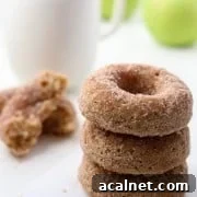 Close up of stack of three apple donuts next to a cup of coffee and apples