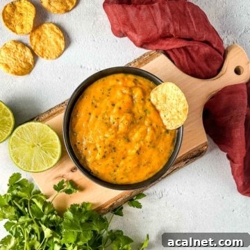 Roasted mango habanero salsa on a wooden cutting board surrounded by lime and cilantro.