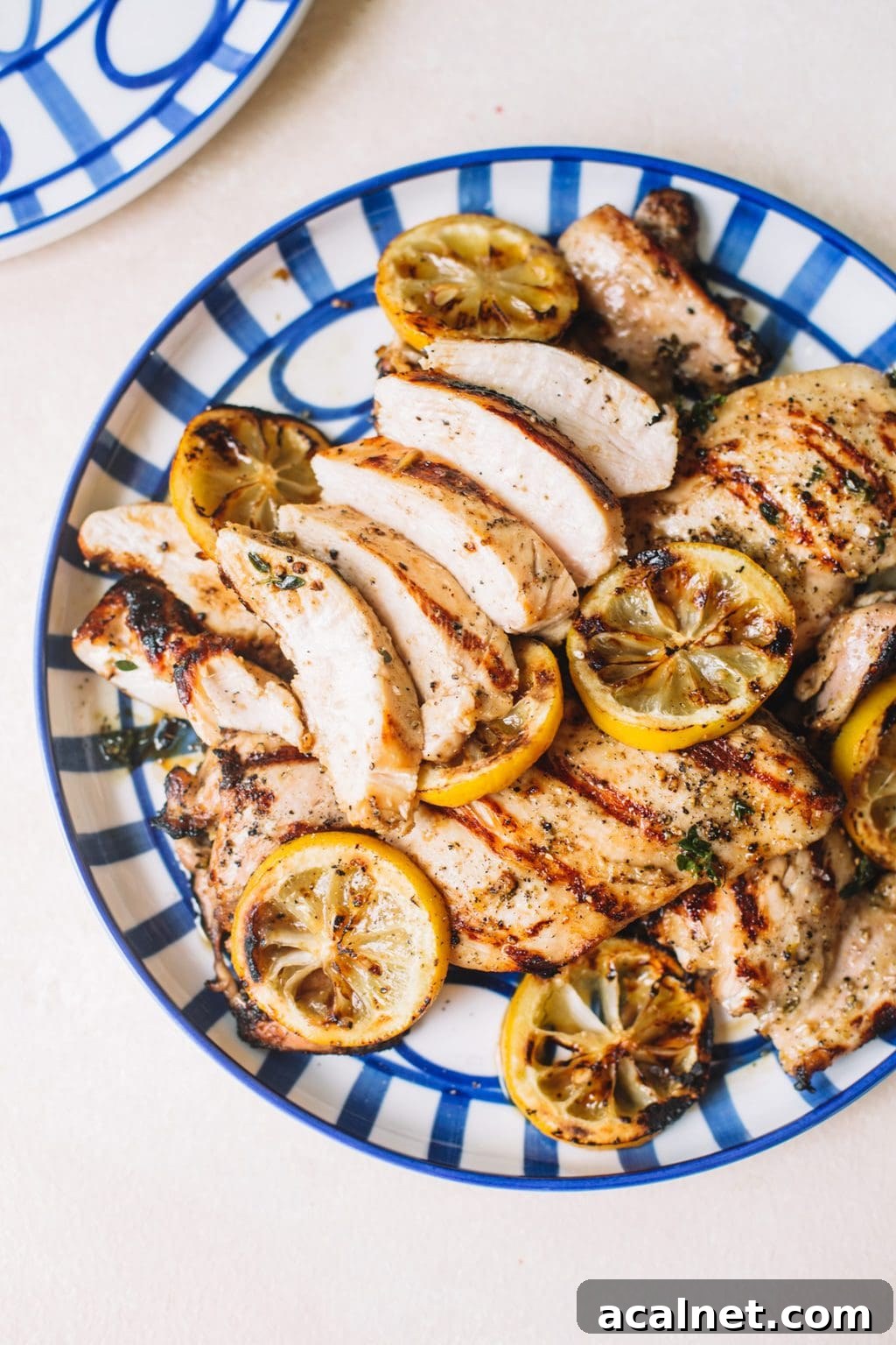 Citrus Grilled Chicken with Lemon Herb Marinade 6 sliced lemon chicken recipe with lemon wheels on blue striped plate