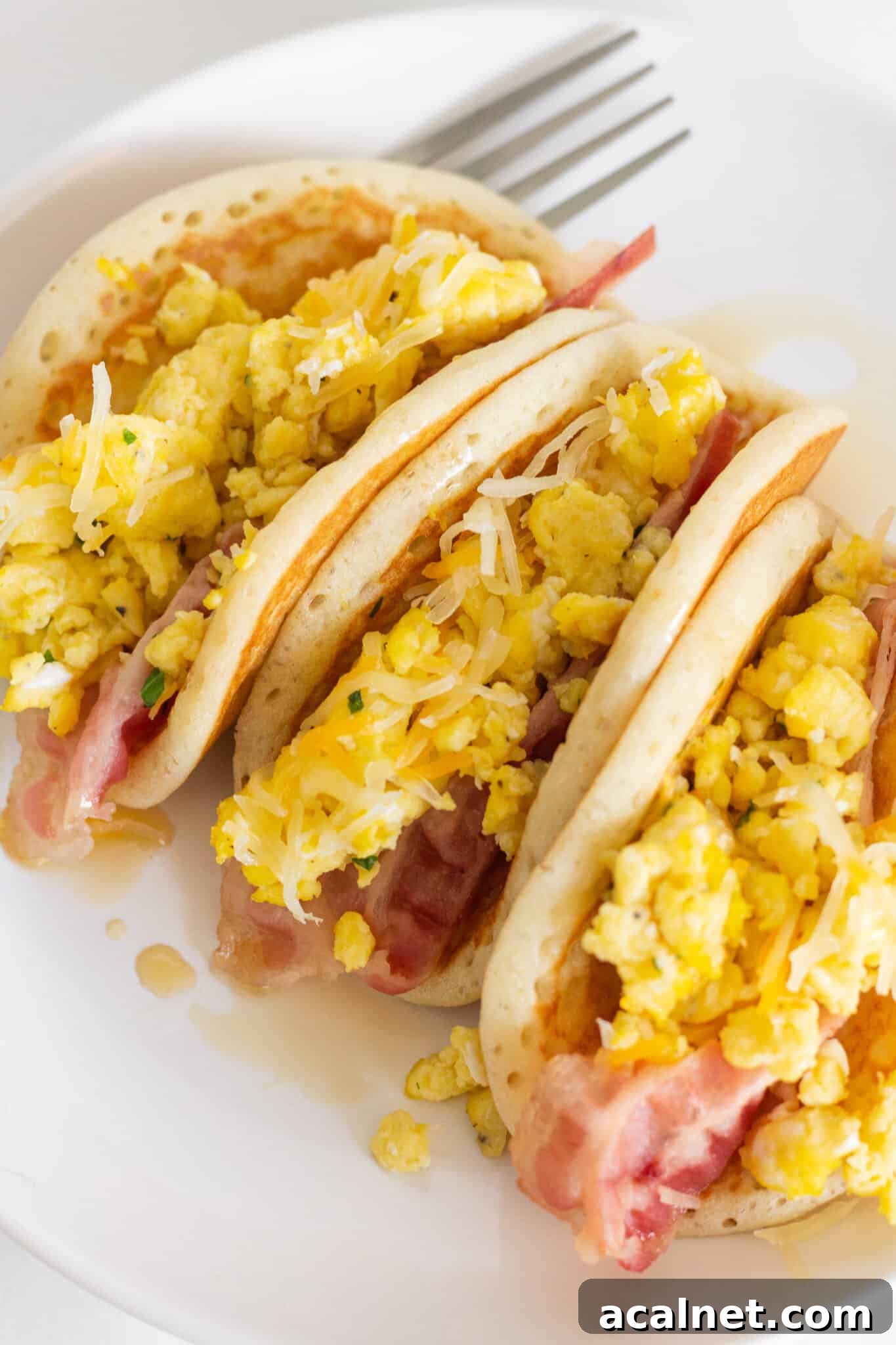 Fluffy Pancake Tacos: Sweet and Savory Breakfast Wraps 2 Looking at a plate with two pancake tacos with bacon and eggs.