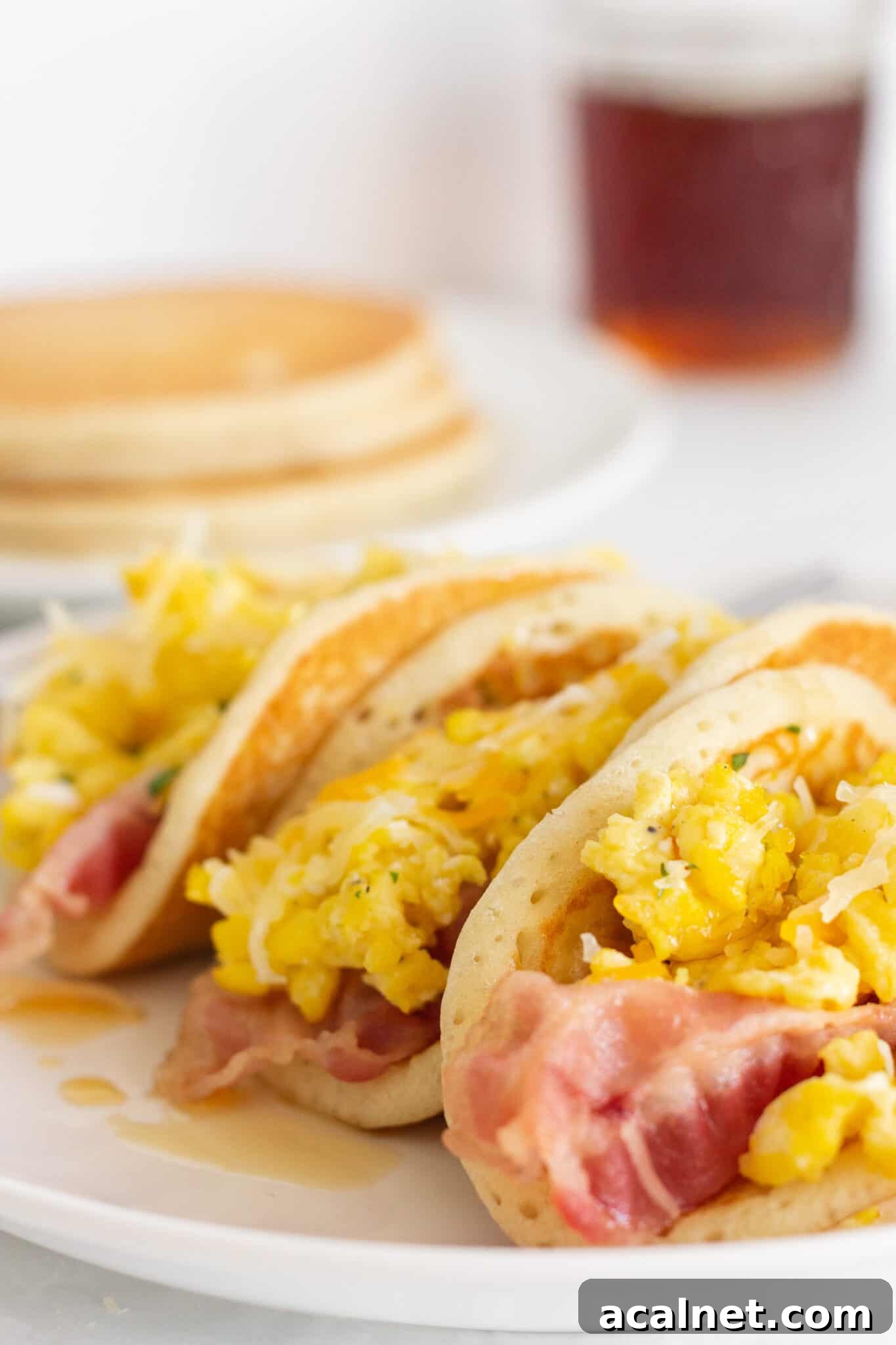 Fluffy Pancake Tacos: Sweet and Savory Breakfast Wraps 3 Pancake tacos on a plate with maple syrup.