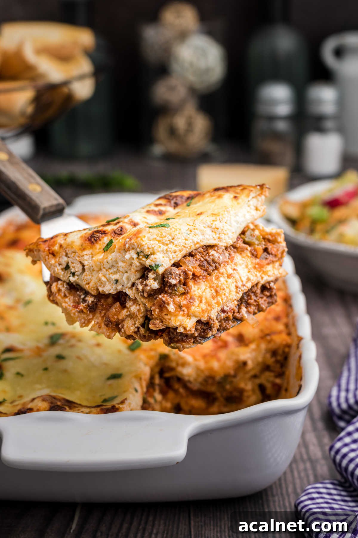A scoop of venison lasagna being lifted out of the baking dish.