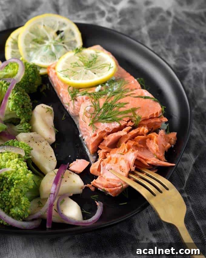 Pressure Cooker Lemon Butter Salmon with vegetables on black plate with gold fork