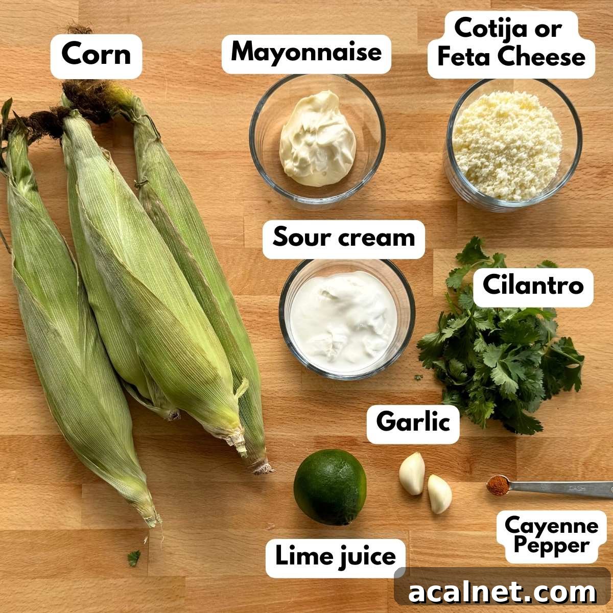 Mexican Street Corn Cups Recipe – Creamy Elote in a Cup 3 Labeled ingredients to make the recipe: 4 cobs of corn, mayonnaise, Cotija cheese, sour cream, cilantro, 2 garlic cloves, a lime, and cayenne pepper on a measuring spoon.