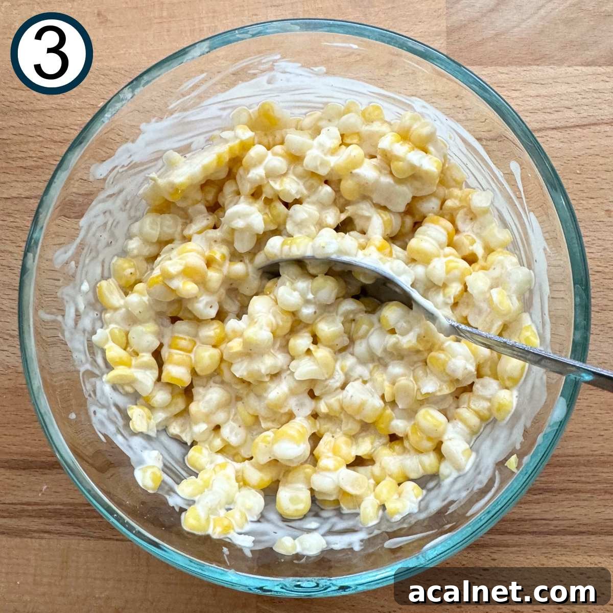 Mexican Street Corn Cups Recipe – Creamy Elote in a Cup 6 Corn kernels mixed with lime crema mixture in a glass bowl.