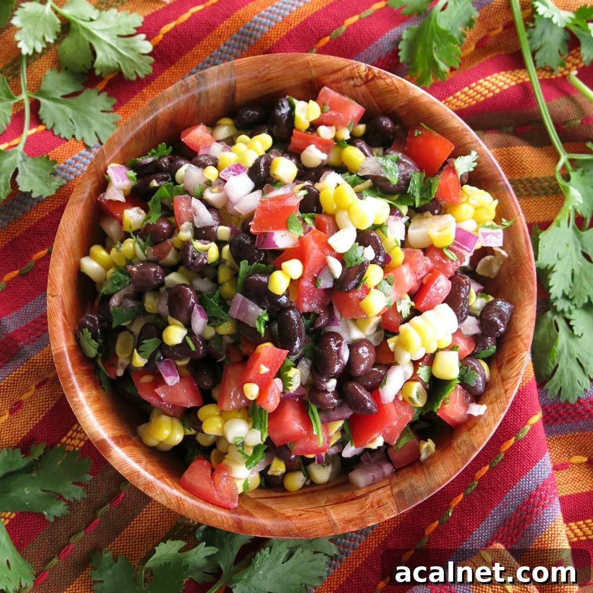 Fresh corn and black bean salsa with red wine vinegar dressing in a wooden bowl.