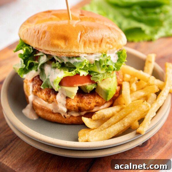 Crispy Shrimp Po' Boy Sandwich Recipe for Classic New Orleans Flavor 12 A shrimp burger on a plate with fries on a tabletop.