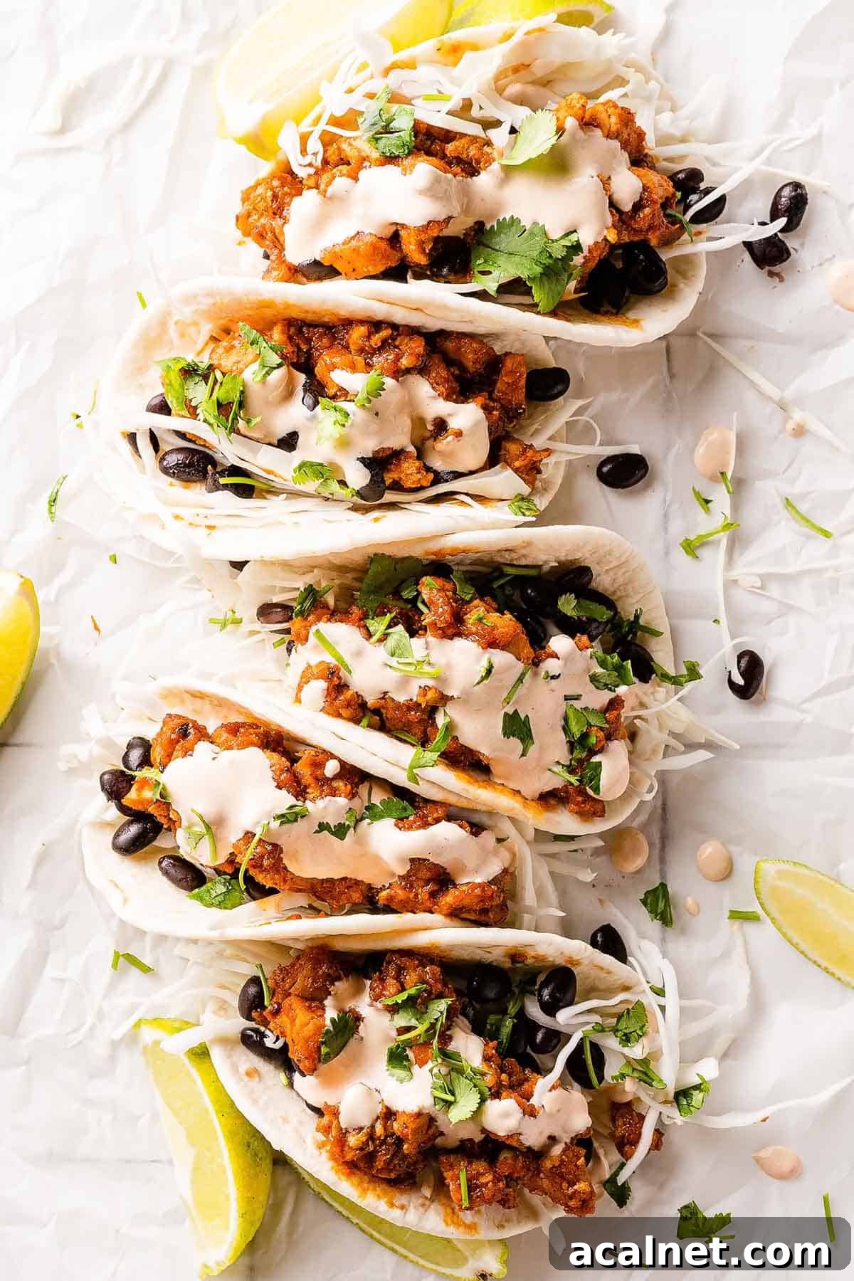 chipotle chicken tacos on paper with limes on the side