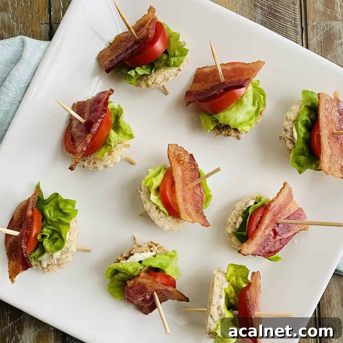 Toothpicks with bacon, lettuce and tomatoes on a plate.