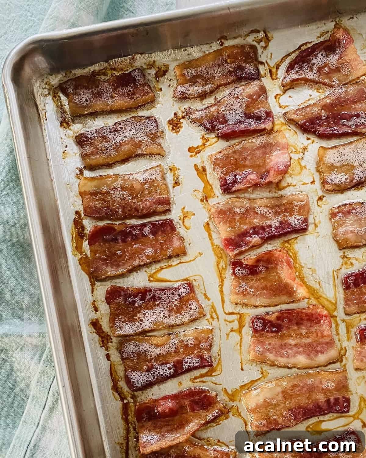 Cooked crispy pieces of bacon on a baking sheet.