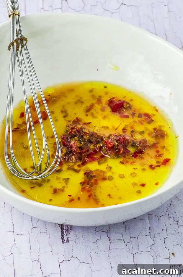 Close up of the salad dressing in a bowl, with a metal whisk