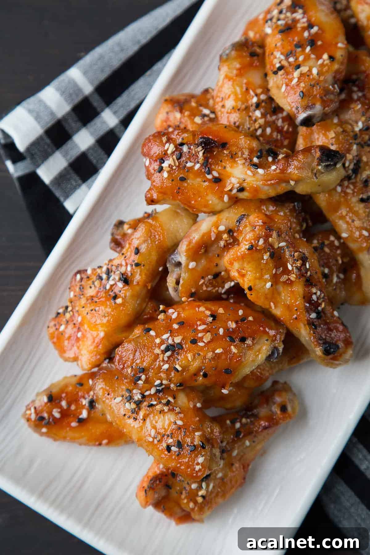 sweet and spicy wings topped with everything bagel seasoning on a white platter.