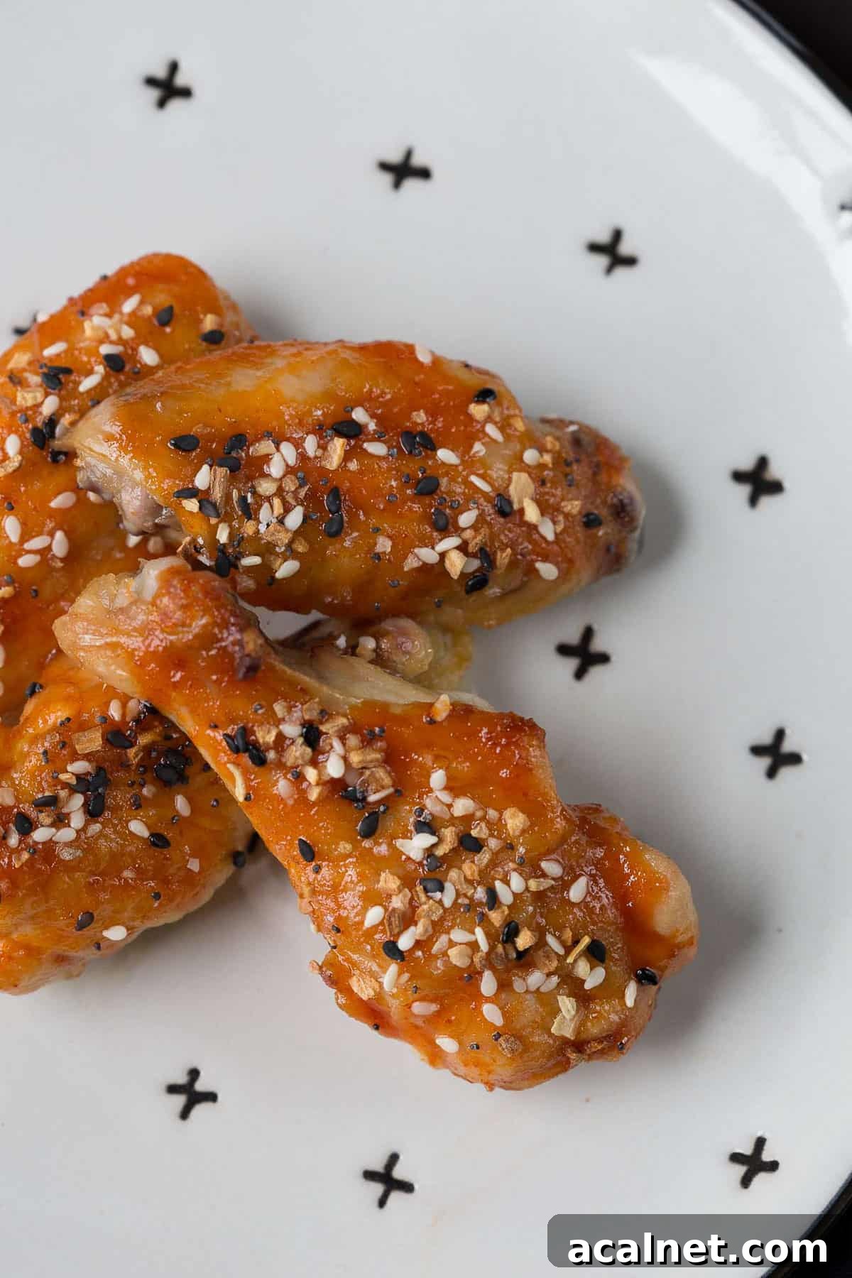wings topped with everything bagel seasoning on a white plate with decorative X's on it.