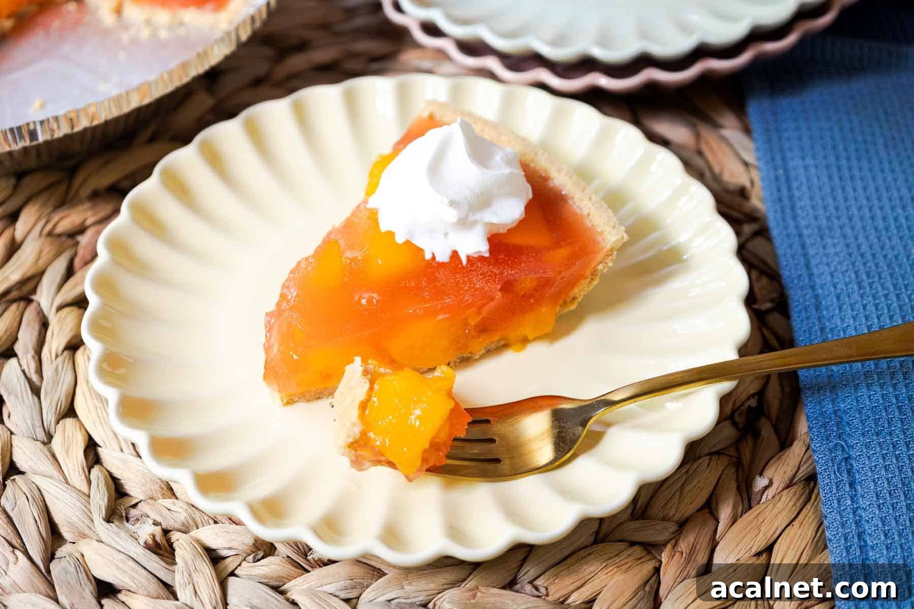 A slice of peach Jello pie with whipped topping and a bite on a fork.