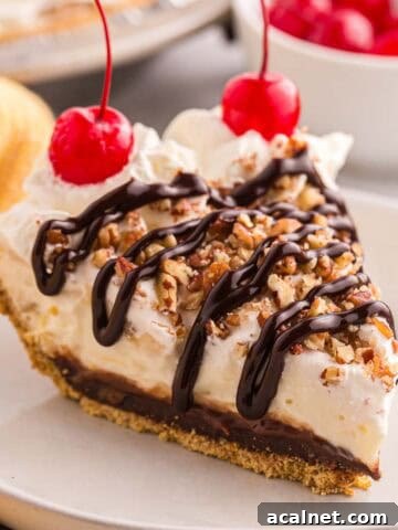 Slice of banana split pie topped with whipped cream, chopped pecans, chocolate syrup, and cherries.