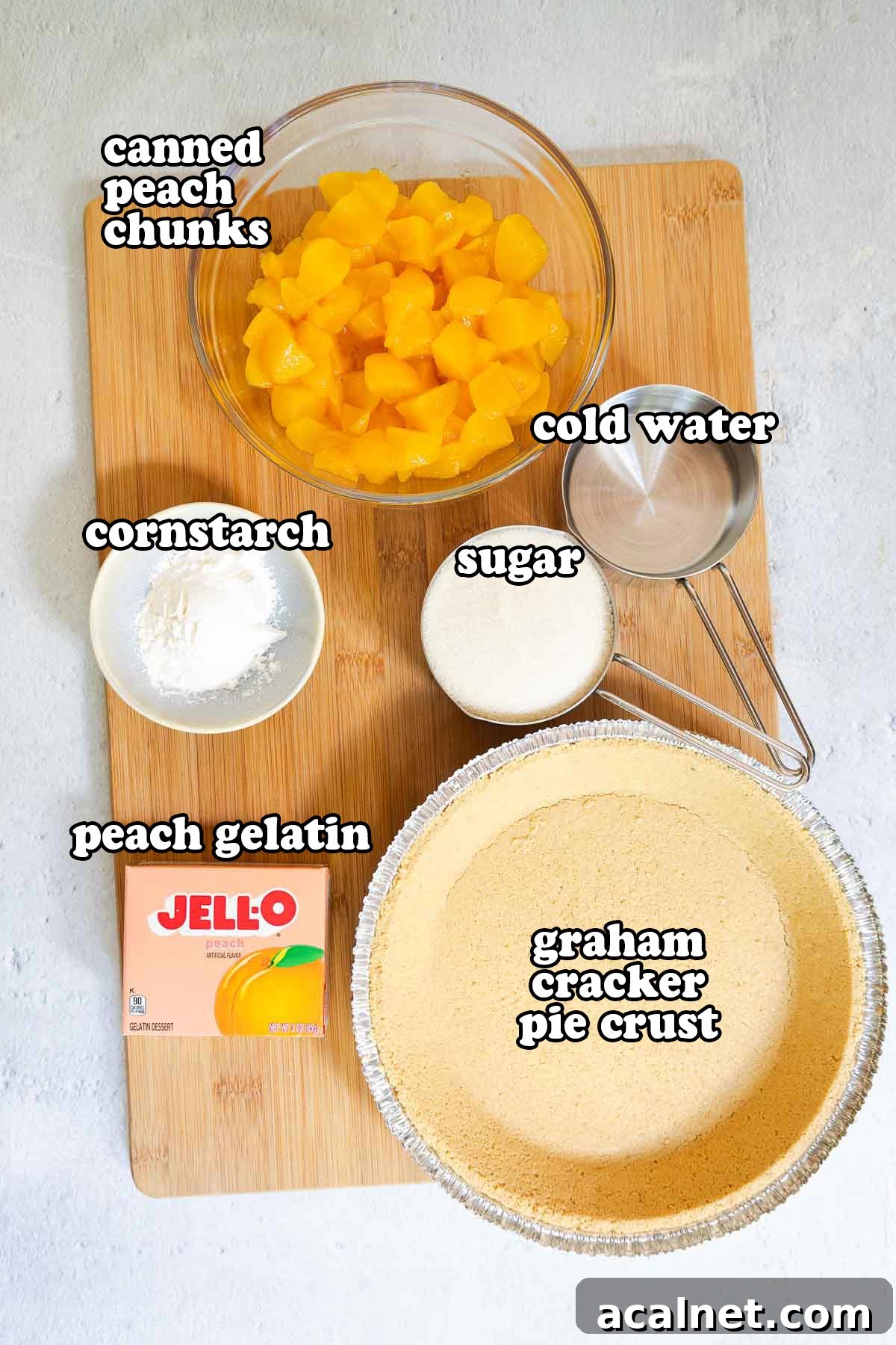 Ingredients on a cutting board: canned peach chunks, cold water, cornstarch, sugar, peach gelatin, and graham cracker pie crust.