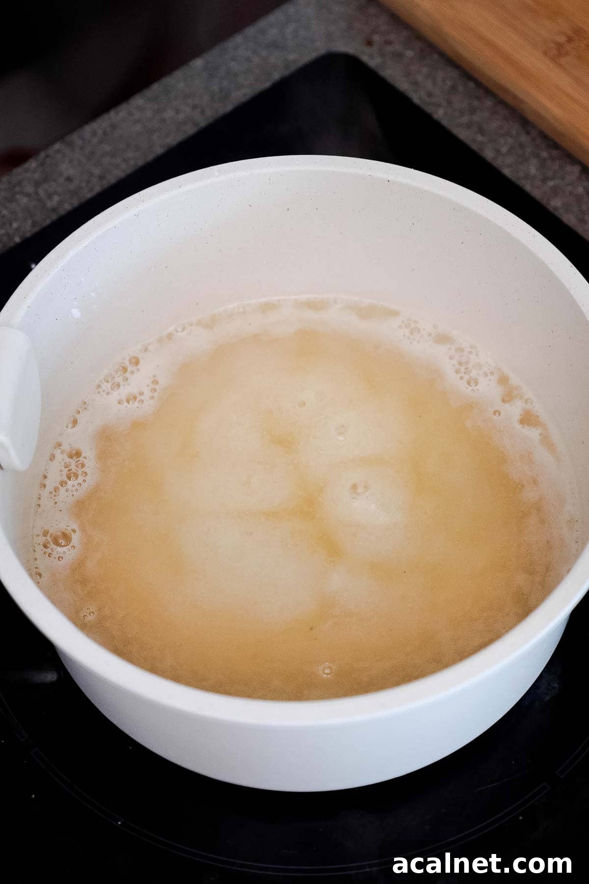 A white pot with a bubbling pale liquid.