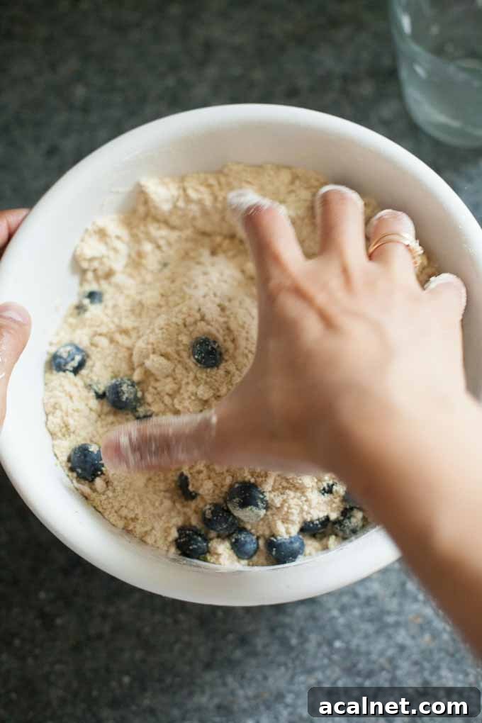 Closeup of the author using her fingers to finish blending the butter into the dry mix with her fingers.