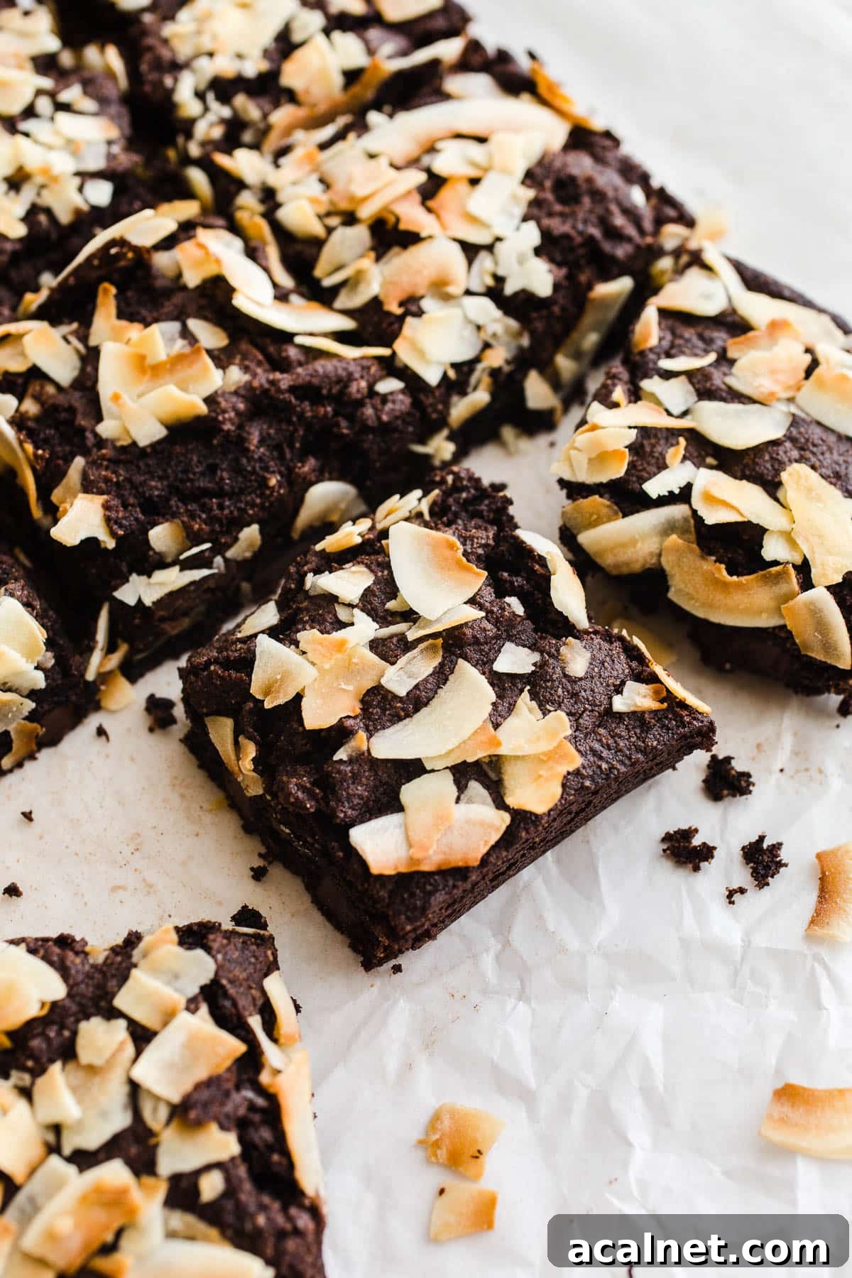 Chocolate coconut bars on white parchment paper.